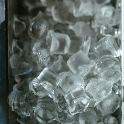 A detailed view of crystal clear ice cubes in a metal tray, perfect for refreshing drinks.